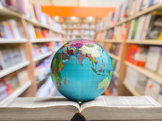 Globe on top of book, with more books in the background