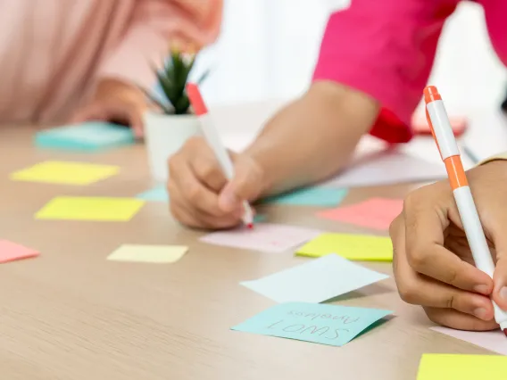 People writing words on sticky notes