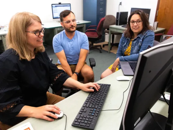 Image of three people looking at a computer screen