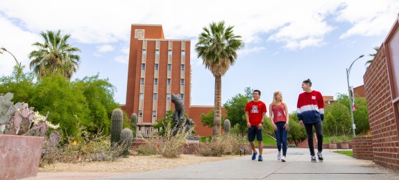 Students in UArizona-branded shirts walking near the campus mall