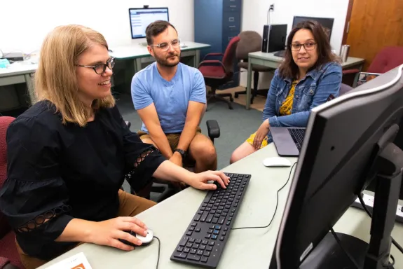 Image of three people looking at a computer screen
