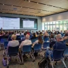 An image of a person giving a presentation to a room full of people.